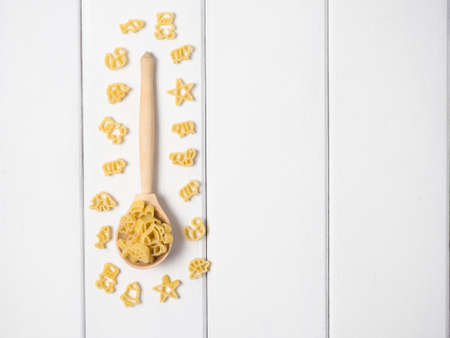 raw children's pasta in the form of different animals, stars and bells on a wooden spoonの写真素材