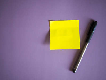 blank yellow paper sticker for notes and pen on purple backgroundの写真素材