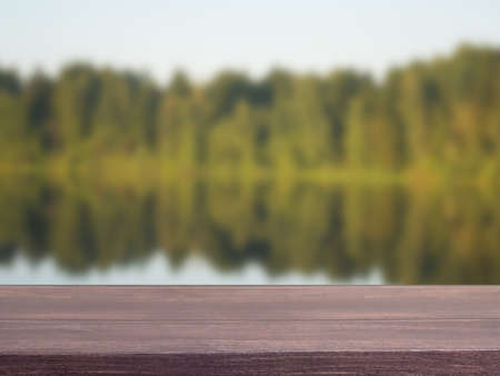 Empty wooden table with forest and pond bokeh for catering or food, product showcase mockup templateの写真素材