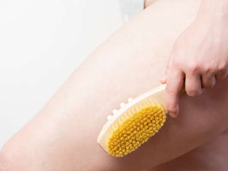 close-up Woman doing leg massage with wooden soft massage brush for body and legs. Cellulite prevention, skin care.の写真素材