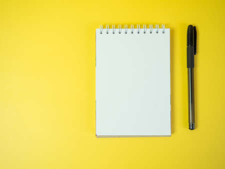 Notebook and pen, on a yellow background. top view copy space