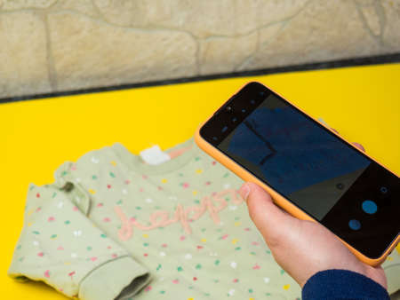 A woman photographs children's clothing for sale online. The concept of selling clothes online. second hand clothes.の写真素材
