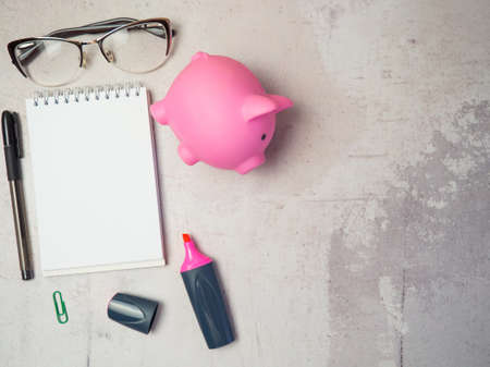 piggy bank on the table with notepad and glassesの写真素材