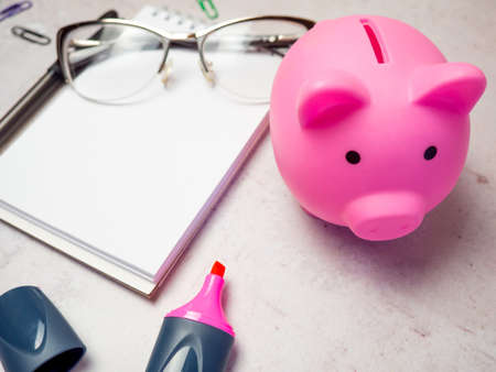 piggy bank on the table with notepad and glassesの写真素材