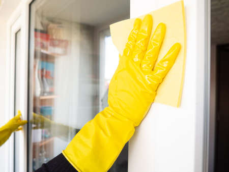 girl in yellow gloves washes windows at home close-up