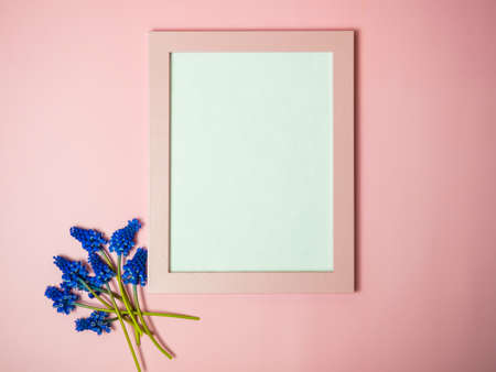 fresh purple flowers with blank pink photo frame on pink background. Mockup for an idea. Empty space for text or imageの写真素材