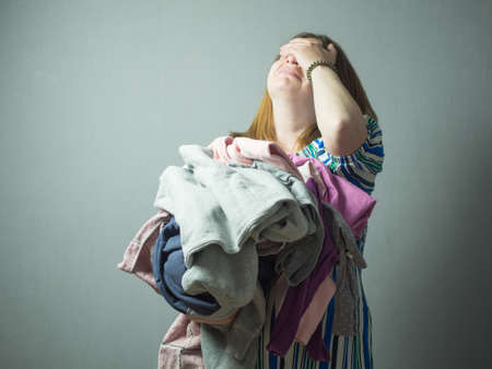 the girl is tired of household chores, the housewife is stressed during work, ironing clothesの写真素材