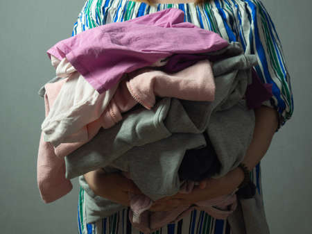 girl with a pile of laundry on a gray backgroundの写真素材