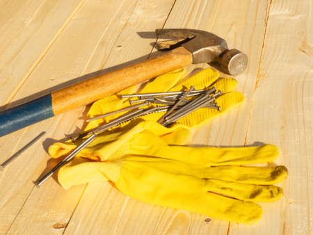 hammer nails and gloves on wooden surface woodworking conceptの写真素材