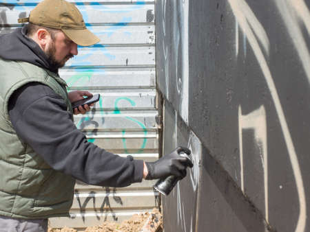 a guy in a cap draws graffiti, the concept of street urban art
