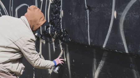 guy in a hood and black glasses writes graffitiの写真素材