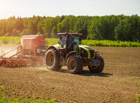 Collective farmers sow, sow crops in the field. big tractor working in the field, harvesting, doing...