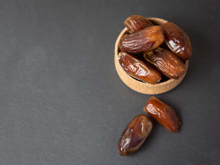 dates in a wooden bowl on gray slate copy spaceの写真素材