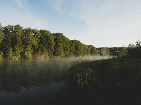 Sunrise over a foggy lake. early morning on the river. sunrise and mist over water and trees with...