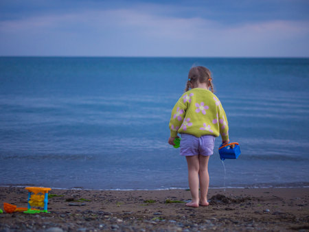 little girl plays on the beach in the eveningの写真素材