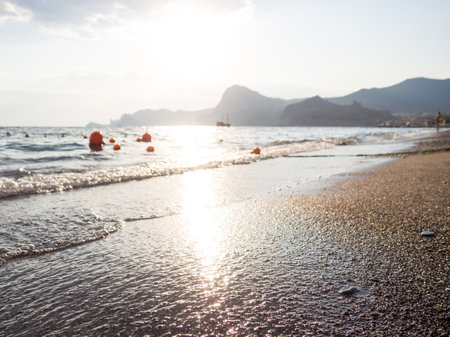 Sand beach surface with wet pebbles and white water waves with foam. Beautiful nature backgroundsの写真素材