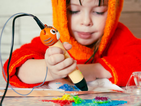 Children's hands make a craft using a 3D printing pen. A girl draws with a 3D pen.