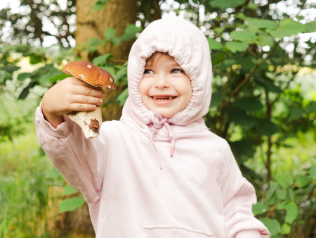 girl in the forest shows red mushroomの写真素材