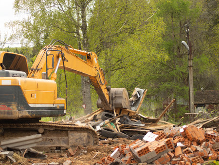 yellow excavator demolishes old buildings with its bucketの写真素材