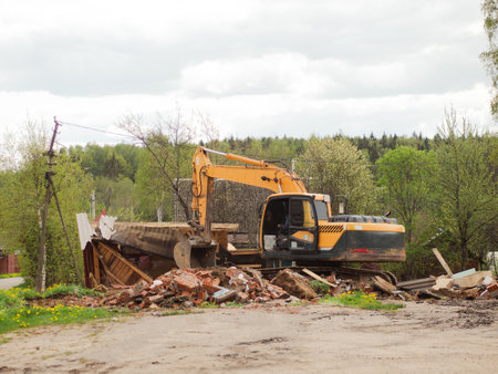 yellow excavator demolishes old buildings with its bucketの写真素材