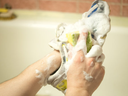 man washes sneakers with a brushの写真素材