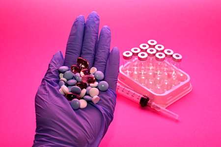 hand in a blue medical glove pills on a pink background. human and veterinarian medicine concept