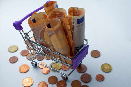 Baskets with five folded 50 euro bills. Toy shopping baskets on a white background. Shopping carts. concept of spending money in a store.の写真素材