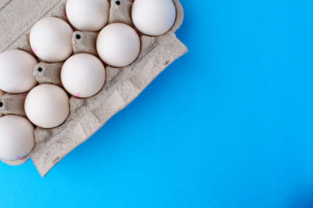 Packaging of white chicken eggs on a blue background. Preparing for Easterの写真素材