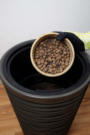 In a small flower pot, expanded clay for plants. Expanded clay is poured from one pot into another...