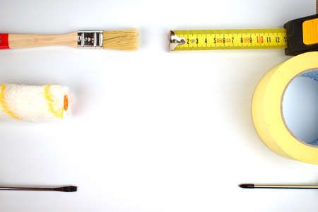 Tape measure, paintbrush, roller, screwdrivers and yellow tape. Renovation concept. Copy space. Flat lay.の写真素材