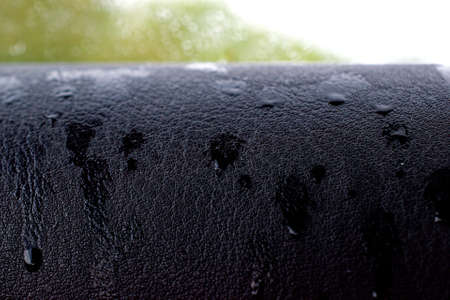 Raindrops on black leather. Copy space.