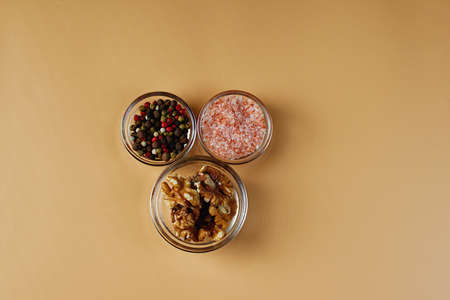 Bowls with pink Himalayan salt, colored peppers and walnuts on an orange background. Salad ingredients.の写真素材