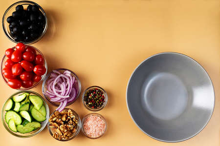 Seven bowls with tomatoes, black olives, cucumbers, colored peppers, pink salt, onion and walnuts.の写真素材