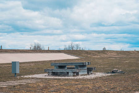 A cozy place for a picnic in the summer - wooden table, benches and trash can, near a campfire pit, Latvia.の写真素材