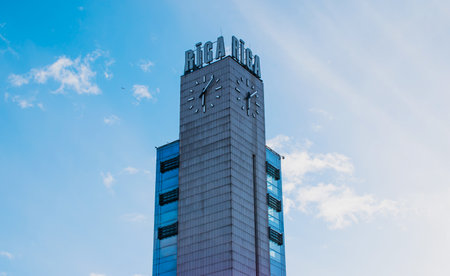 Riga, Latvia - March 29 2022: Clock tower in the shopping center Origo and railway station building in the center of Riga.のeditorial素材