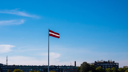 Latvian Flag Hang On Flagpole Against Blue Sky, On Banks Of Daugava River.の写真素材