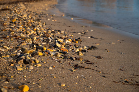 Close-Up Of Sandy Beach With Large Stones Of Ionian Sea In Moraitika, Corfu, Greece At Sunrise. The Coast is Washed by Water.の写真素材