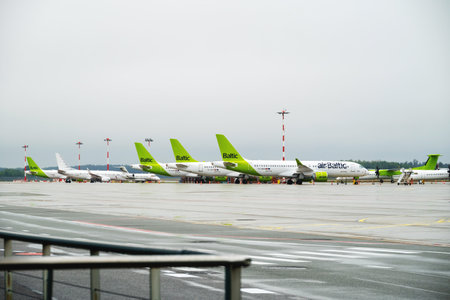 Riga, Latvia - 09 29 2022: View of Riga Airport On Green Planes of AirBaltic. Parking Lot For Aircraft, Against Backdrop Of Cloudy Weather.のeditorial素材