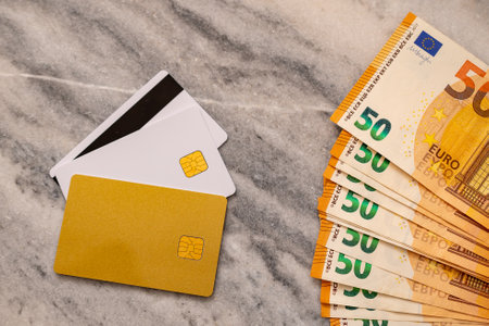 Close-Up Part Of 50 Euro Banknotes And Bank cards. Concept Of Comparing Cash And Non-Cash Money.の写真素材