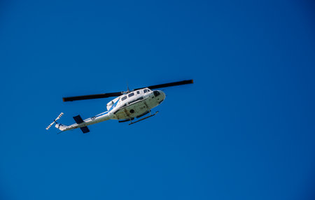 Kerkyra, Greece - 09 24 2022: Bottom view on white helicopter flies over the island of Corfu against a clear blue sky.のeditorial素材