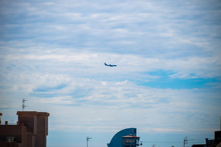 Barcelona, Spain - May 26 2022: Plane flies over the rooftops heading for Barcelona International Airport.のeditorial素材