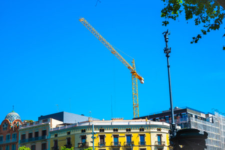 Barcelona, Spain - May 26 2022: Yellow construction cranes over rooftops in Barcelona.のeditorial素材