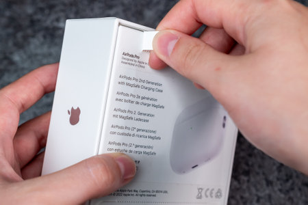 Jurmala, Latvia - 21 09 2023: Unboxing new Apple gadget. Woman tears off a protective strip in a box with new headphones - AirPods Pro 2 generation.のeditorial素材
