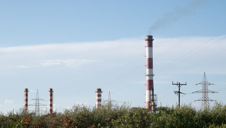 A row of tall red and white power plants are visible in the distanceの写真素材