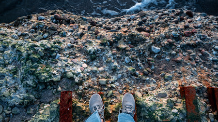 A person is standing on a ledge with their feet on a railingの写真素材