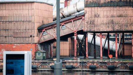 A large industrial building with a red roof and a white pipeの写真素材