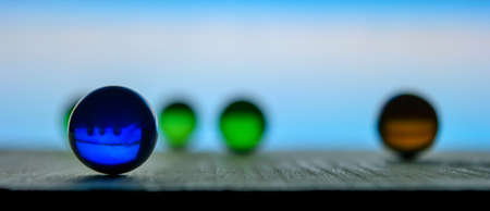 Photo of many color glass balls on wooden board on blurred backgroundの写真素材