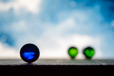 Photo of many color glass balls on wooden board on blurred backgroundの写真素材