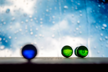 Photo of many color glass balls on wooden board on blurred backgroundの写真素材