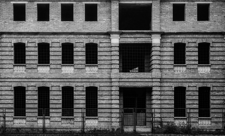 Photo of old unfinished brown building with many windows, black and white